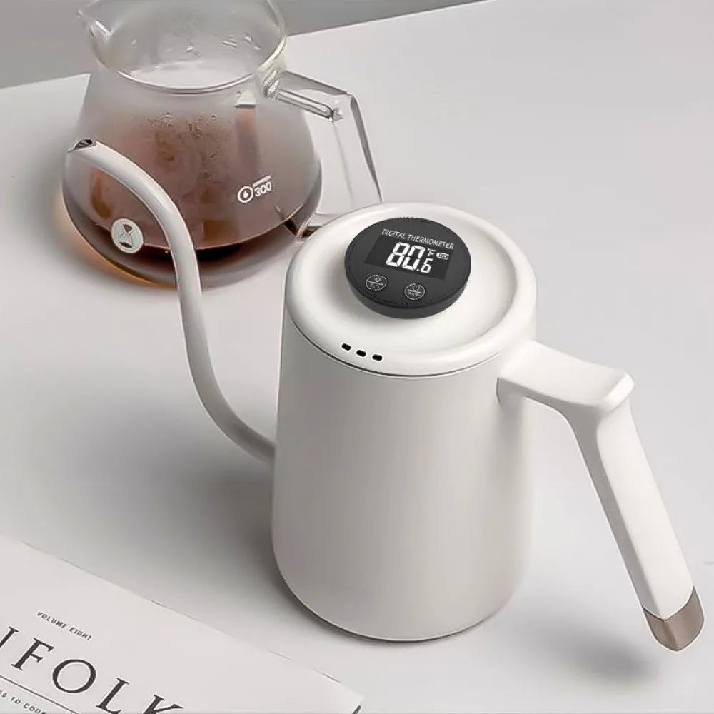 A white electric gooseneck kettle with a digital temperature display on top, shown on a light surface next to a glass coffee carafe.