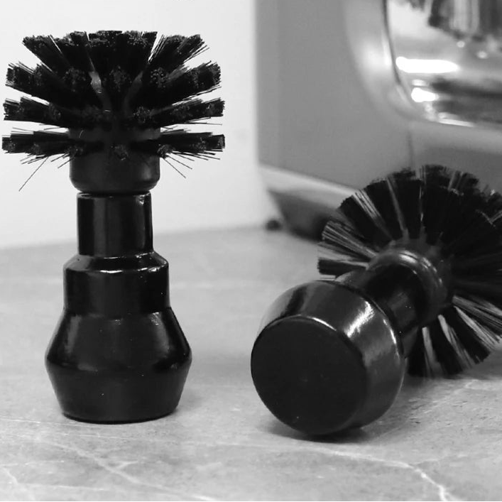 Two black cleaning brushes on a marble surface with 'Cafe Gaga' branding.