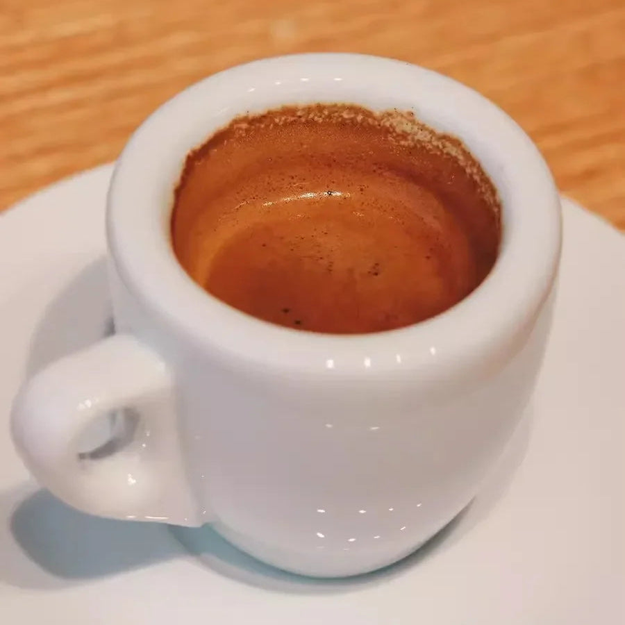 White espresso cup filled with coffee on a wooden surface